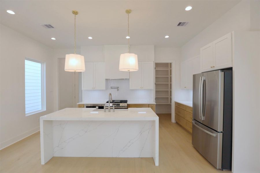 A 3cm waterfall island featuring a continuous quartz surface that elegantly wraps over the edges. The back of the island is fully finished in quartz, highlighting the stone’s natural veining and creating a seamless, high-end aesthetic that enhances the overall kitchen design. A 3cm waterfall island featuring a continuous quartz surface that elegantly wraps over the edges. The back of the island is fully finished in quartz, highlighting the stone’s natural veining and creating a seamless, high-end aesthetic that enhances the overall kitchen design.