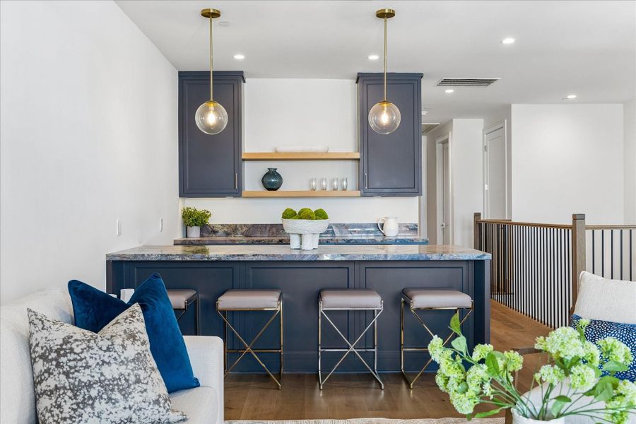 The wet bar has a dynamic Marbella quartzite slab counter. The black quartz sink and Brizo Odin bar faucet will aid you in preparing snacks or cocktails. The opening will house a beverage cooler.