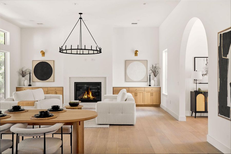 Living room featuring light wood-type flooring, a high ceiling, and a glass covered fireplace Living room featuring light wood-type flooring, a high ceiling, and a glass covered fireplace