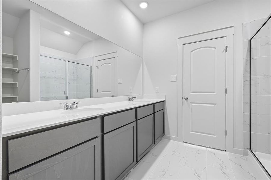 Bathroom featuring a marble finish shower, light marble finish flooring, double vanity, and a closet