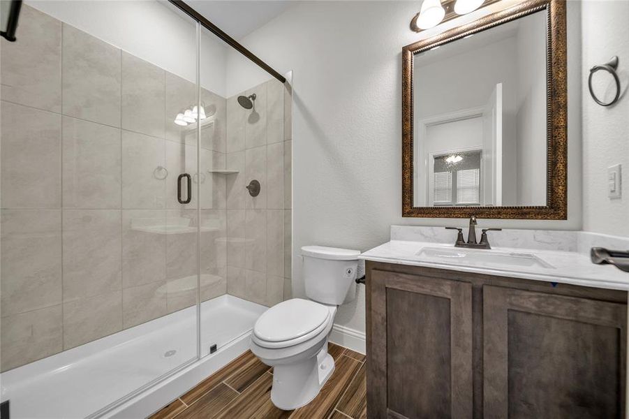 Bathroom with vanity, a shower stall, and wood finish floors Bathroom with vanity, a shower stall, and wood finish floors