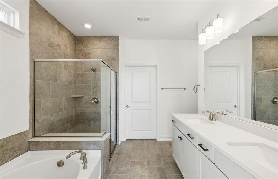 Elegant owner's suite with dual vanity and oversized shower*real home pictured