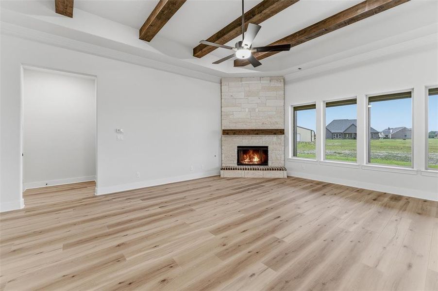 Spacious room featuring wood-finish flooring and a stone-clad fireplace with a wood mantle Spacious room featuring wood-finish flooring and a stone-clad fireplace with a wood mantle