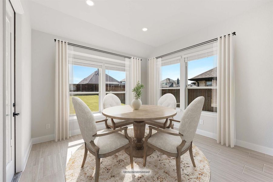 Bright dining nook with round wood table, four upholstered chairs, and large windows overlooking backyard