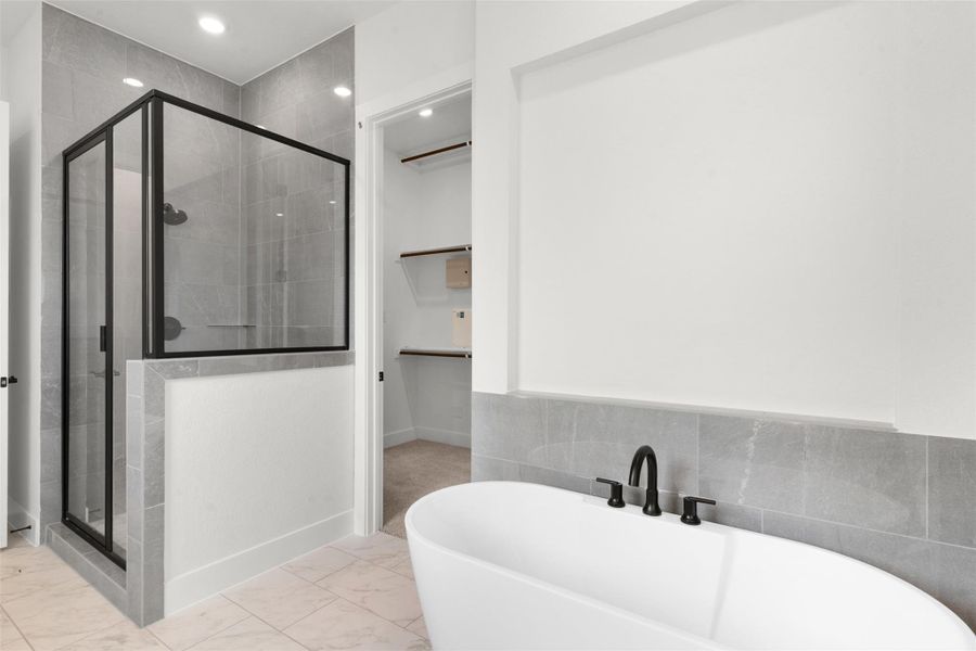 Full bath with a spacious closet, a freestanding bath, light marble finish flooring, a shower stall, and recessed lighting