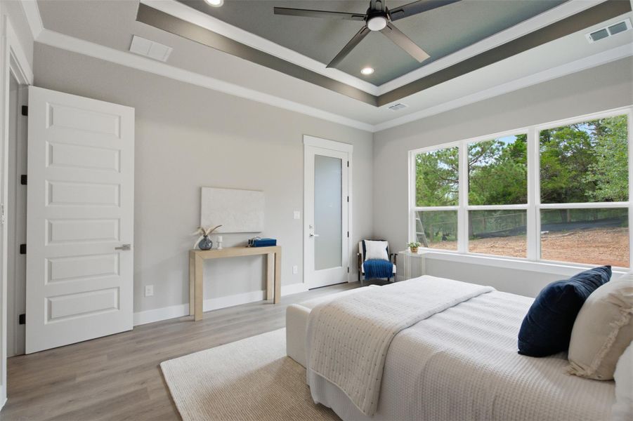 A tranquil primary bedroom with a soaring tray ceiling and abundant natural light. A tranquil primary bedroom with a soaring tray ceiling and abundant natural light.
