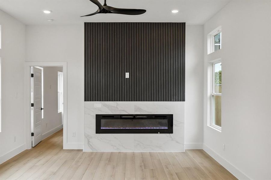 Unfurnished living room featuring a ceiling fan, wood finished floors, a high end fireplace, and recessed lighting