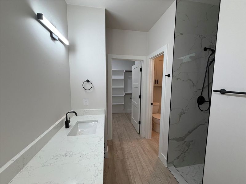 Modern bathroom featuring sleek white countertops, a contemporary vanity, and a sophisticated walk-in shower.