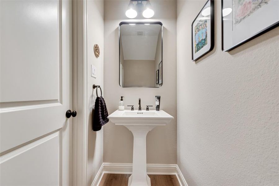 Upgraded pedestal sink with dark-finish faucet and upgraded framed mirror, complemented by upgraded Pergo water tight laminate wood look flooring and white baseboards Upgraded pedestal sink with dark-finish faucet and upgraded framed mirror, complemented by upgraded Pergo water tight laminate wood look flooring and white baseboards