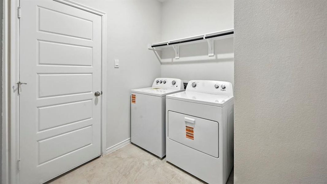 Laundry area with washer and dryer and light tile patterned floors