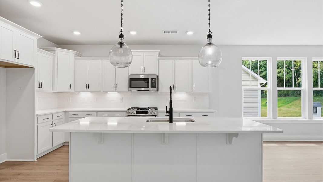 Accomplished kitchen design featuring pendant lighting above a statement island for both prep and gathering