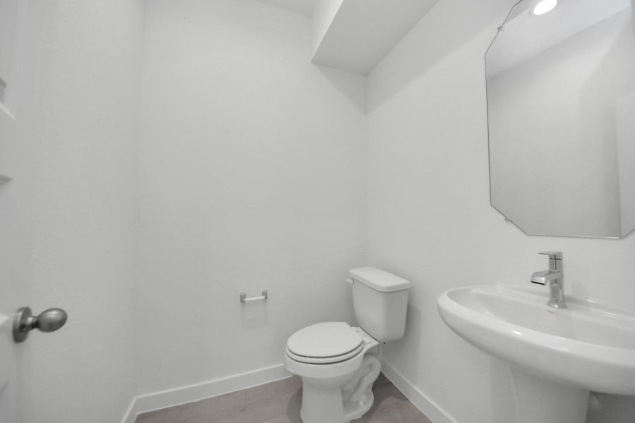 This half bathroom features a stylish pedestal sink, modern hardware, and bright recessed lighting, creating a sleek and inviting space. Sample photo of completed home with similar floor plan. Actual colors and selections may vary. This half bathroom features a stylish pedestal sink, modern hardware, and bright recessed lighting, creating a sleek and inviting space. Sample photo of completed home with similar floor plan. Actual colors and selections may vary.