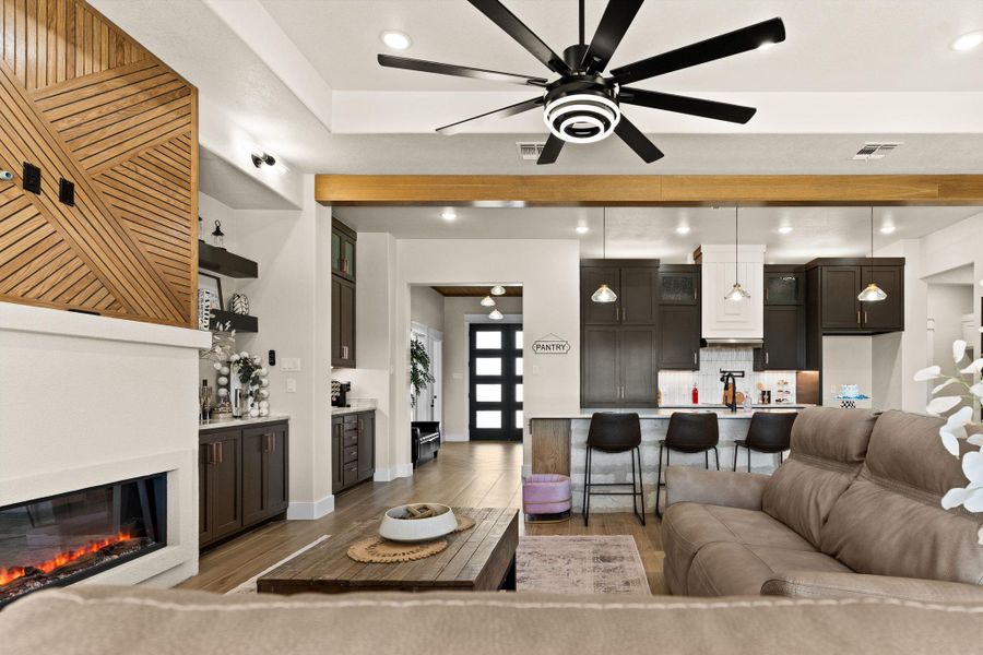 Living area with ceiling fan, light wood-type flooring, baseboards, a glass covered fireplace, and recessed lighting Living area with ceiling fan, light wood-type flooring, baseboards, a glass covered fireplace, and recessed lighting