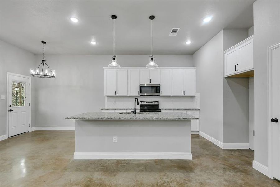 Kitchen featuring finished concrete flooring, light stone counters, white cabinetry, a kitchen island with sink, and recessed lighting
