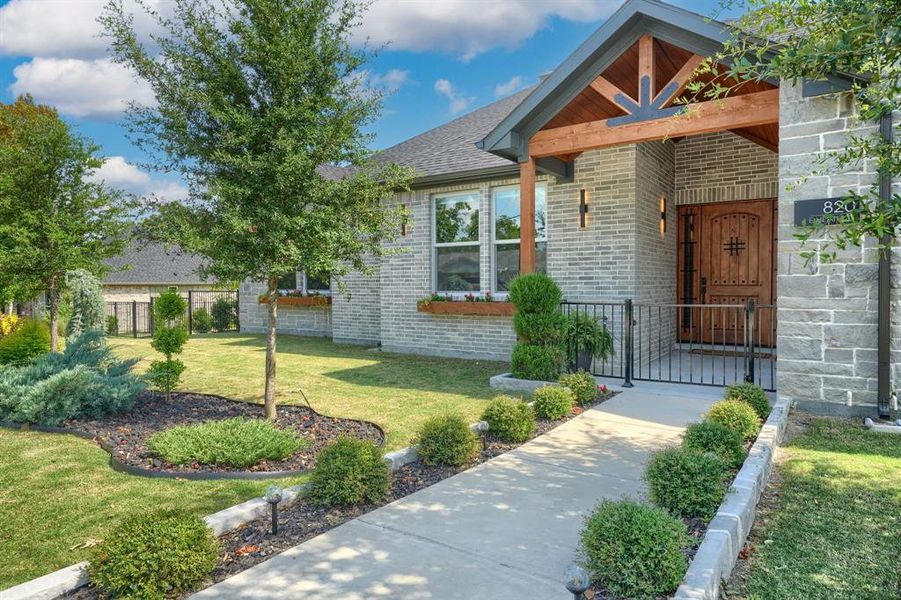 View of exterior entry featuring brick siding, roof with shingles, and a gate View of exterior entry featuring brick siding, roof with shingles, and a gate