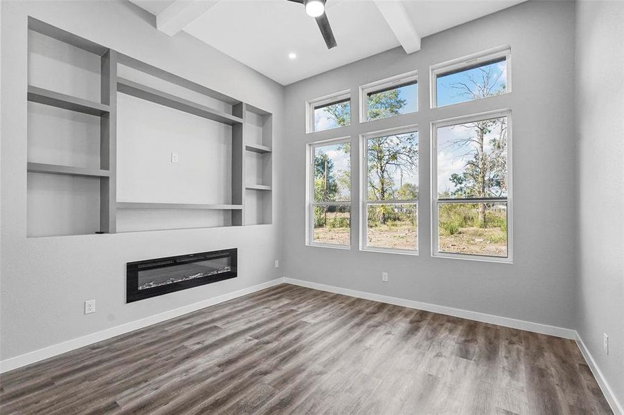 Unfurnished living room featuring beamed ceiling, hardwood / wood-style flooring, built in features, and ceiling fan