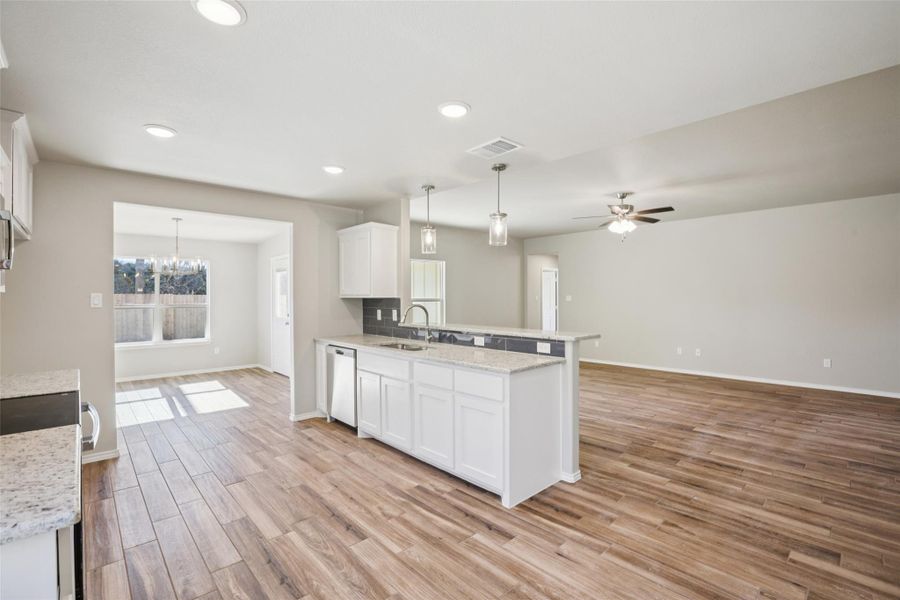Kitchen featuring white cabinetry, light stone countertops, open floor plan, light wood-type flooring, and a peninsula