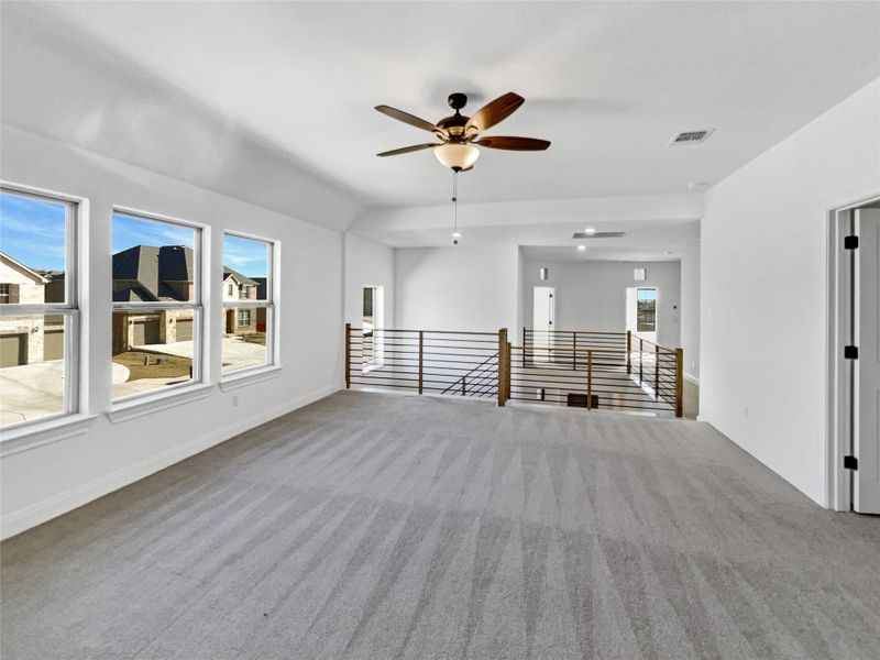 Unfurnished living room featuring visible vents, lofted ceiling, carpet flooring, baseboards, and ceiling fan