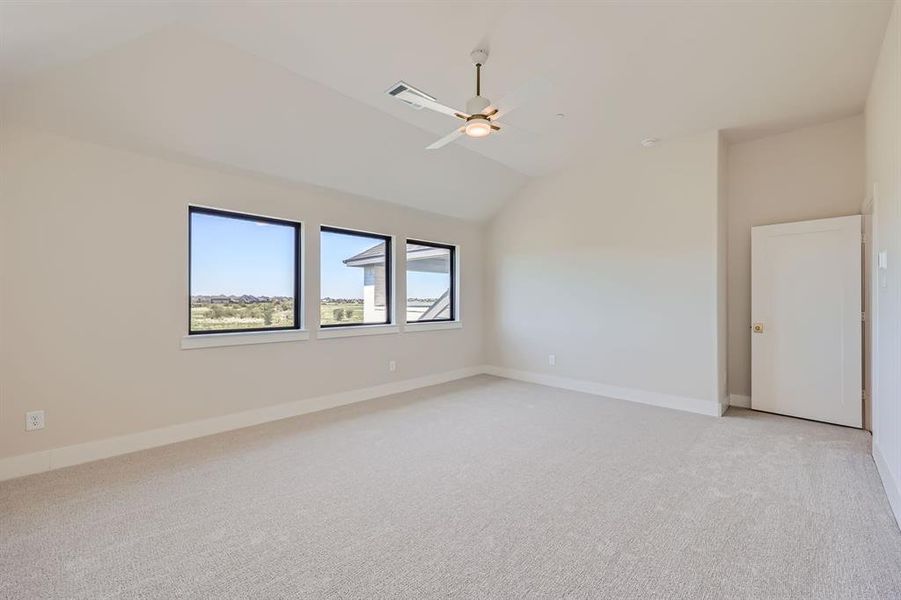 Carpeted spare room with vaulted ceiling and ceiling fan