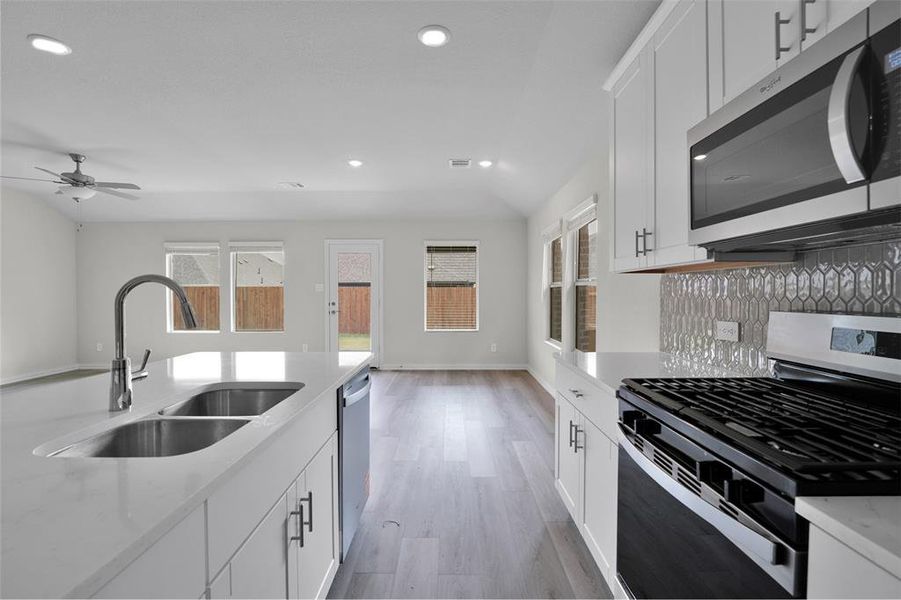 Kitchen featuring stainless steel appliances, white cabinetry, recessed lighting, light stone countertops, and light wood-style floors Kitchen featuring stainless steel appliances, white cabinetry, recessed lighting, light stone countertops, and light wood-style floors
