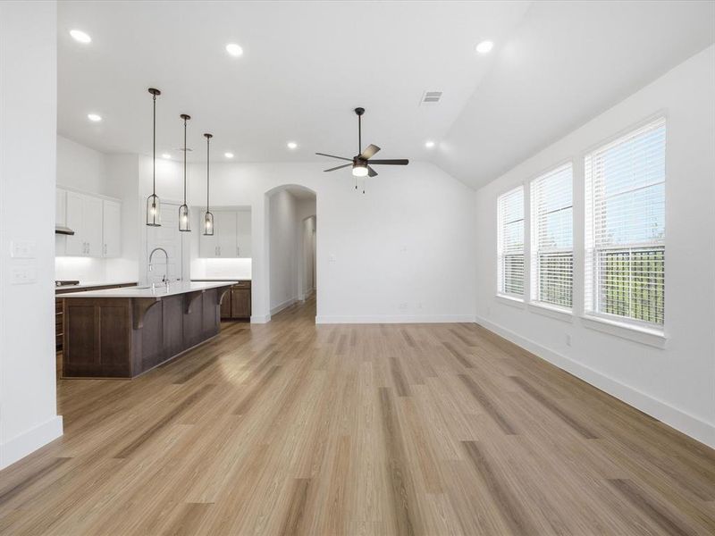 Unfurnished living room featuring arched walkways, light wood-type flooring, lofted ceiling, recessed lighting, and ceiling fan