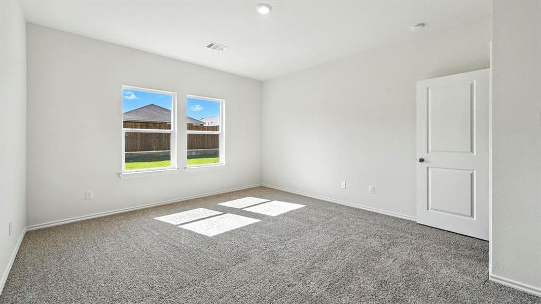 Spacious room with plush gray carpet, bright white walls, two large windows, a two-panel interior door, and recessed lighting
