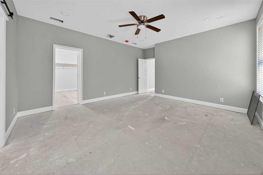 Unfurnished bedroom with a ceiling fan, a walk in closet, and a barn door