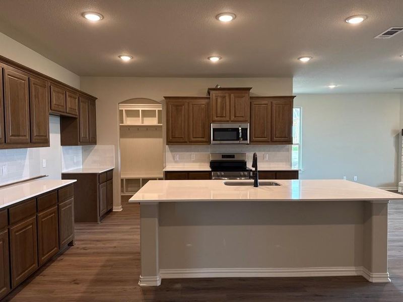 Open-concept kitchen featuring wood-finish flooring, recessed lighting, and a central island with a sink