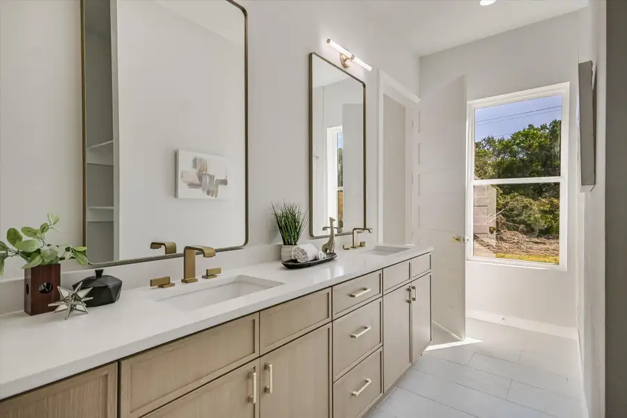 Bathroom with healthy amount of natural light, double vanity, and light tile patterned flooring
