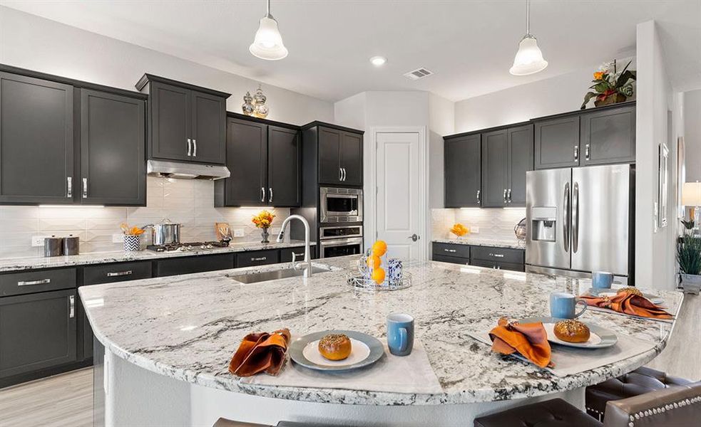 Kitchen featuring stainless steel appliances, a kitchen island with sink, hanging light fixtures, and sink