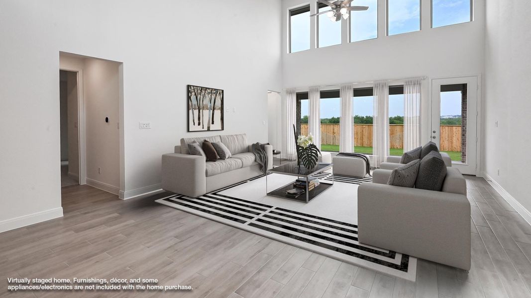 Living area with a high ceiling, baseboards, wood finished floors, and a ceiling fan