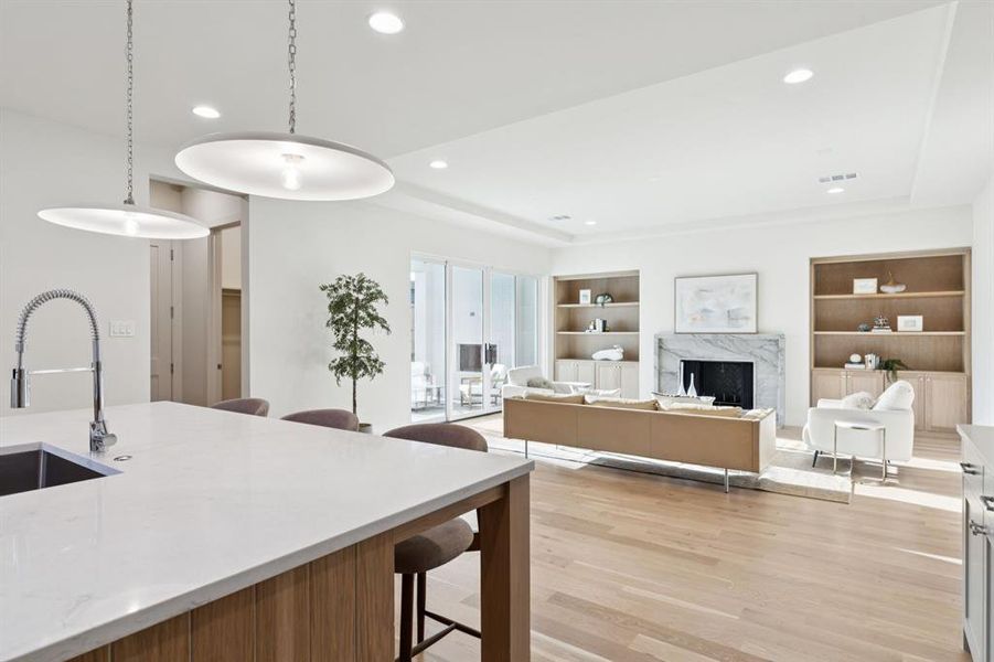 Kitchen featuring light wood-type flooring, a kitchen breakfast bar, recessed lighting, a high end fireplace, and decorative light fixtures