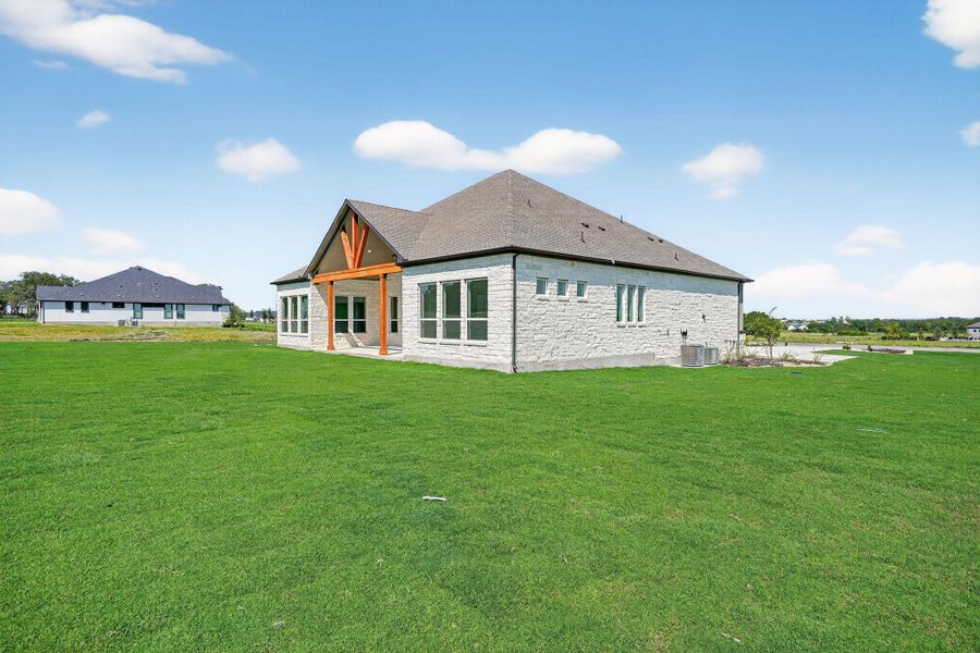 Back of property featuring a patio, a lawn, and stone siding Back of property featuring a patio, a lawn, and stone siding