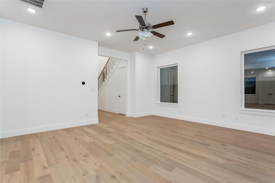 Unfurnished room featuring recessed lighting, light wood-style floors, ceiling fan, and stairway Unfurnished room featuring recessed lighting, light wood-style floors, ceiling fan, and stairway