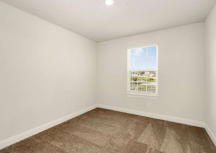 Secondary bedroom with tan carpet and a large window.