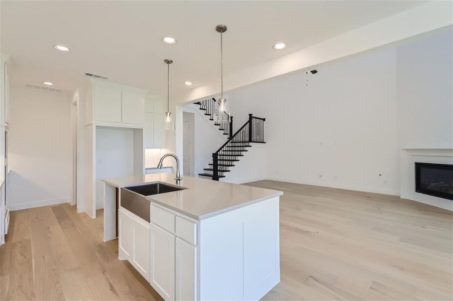 Kitchen featuring white cabinets, sink, an island with sink, and light hardwood / wood-style floors