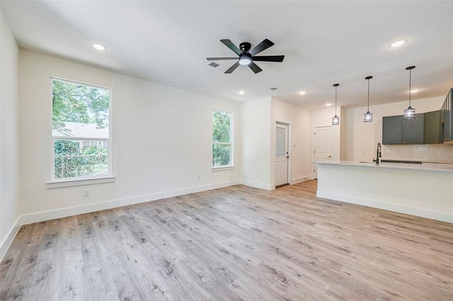 Open-concept living space featuring wood-finish flooring, recessed lighting, and a contemporary ceiling fan Open-concept living space featuring wood-finish flooring, recessed lighting, and a contemporary ceiling fan