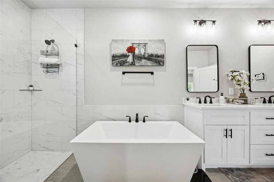 Full bathroom with tile walls, a soaking tub, double vanity, a marble finish shower, and a wainscoted wall