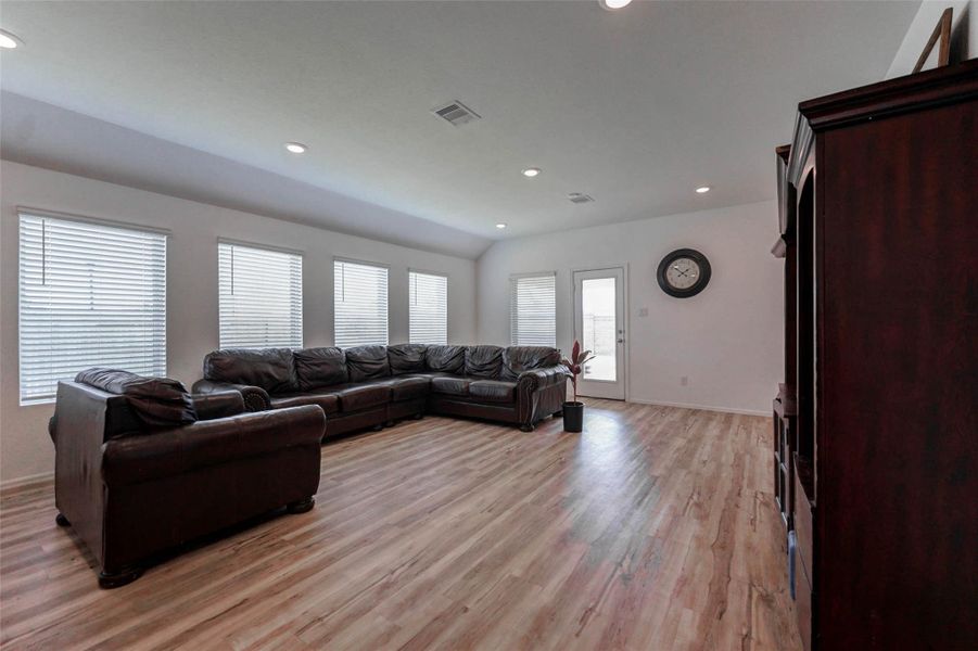 Spacious living room with luxury vinyl plank floors, recessed lighting & backyard access. Natural light pours in through a wall of windows in this open-concept Sunterra home in Katy TX. Spacious living room with luxury vinyl plank floors, recessed lighting & backyard access. Natural light pours in through a wall of windows in this open-concept Sunterra home in Katy TX.