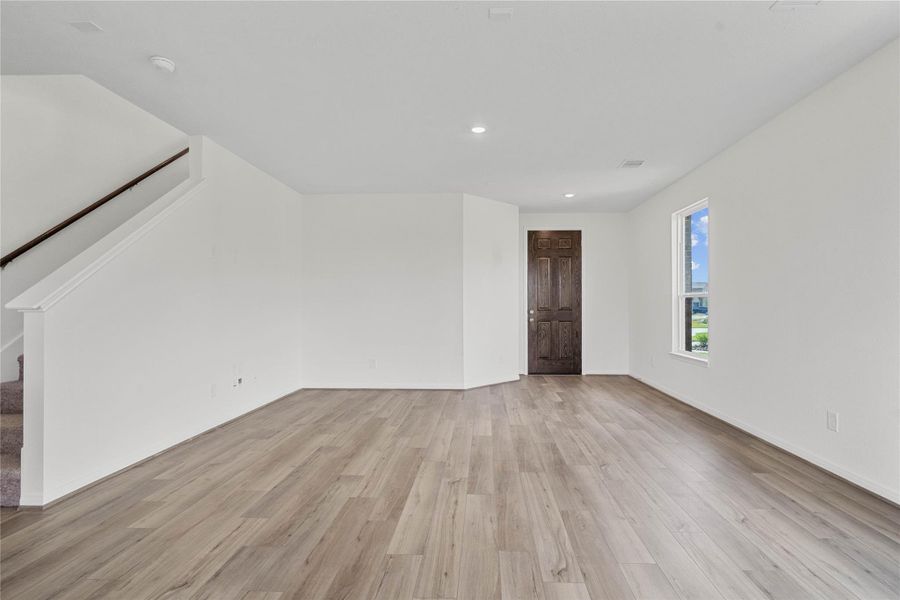 This bright and airy Great Room offers a spacious layout ideal for both relaxing evenings and lively gatherings. Designed for comfort and connection, it features Layton Lake Driftwood vinyl plank flooring, a large window, high ceilings, recessed lighting, and seamless access to the kitchen and dining—perfect for everyday living and entertaining alike.