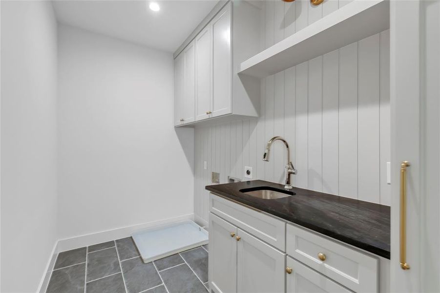 Laundry room featuring cabinet space, electric dryer hookup, recessed lighting, washer hookup, and dark tile patterned flooring