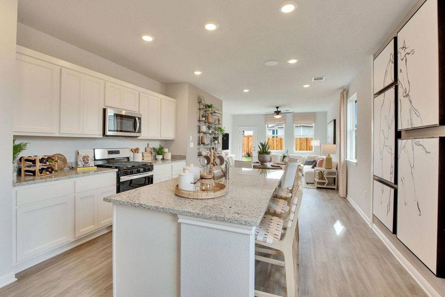 A well-lit kitchen with granite countertops seamlessly transitions into an open-concept living area. A well-lit kitchen with granite countertops seamlessly transitions into an open-concept living area.