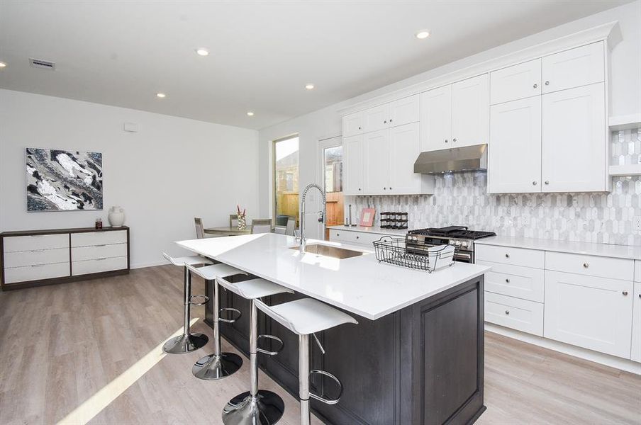 The striking island, with its dark base and extended white counter top, is warmly inviting for quick family snacking.