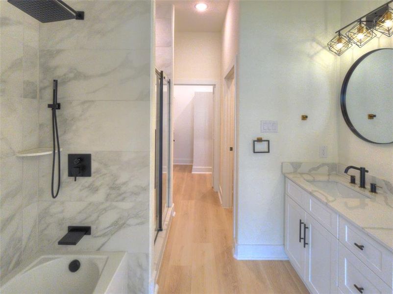 Bathroom featuring a white vanity with a light stone countertop, a modern round mirror, and a three-light fixture