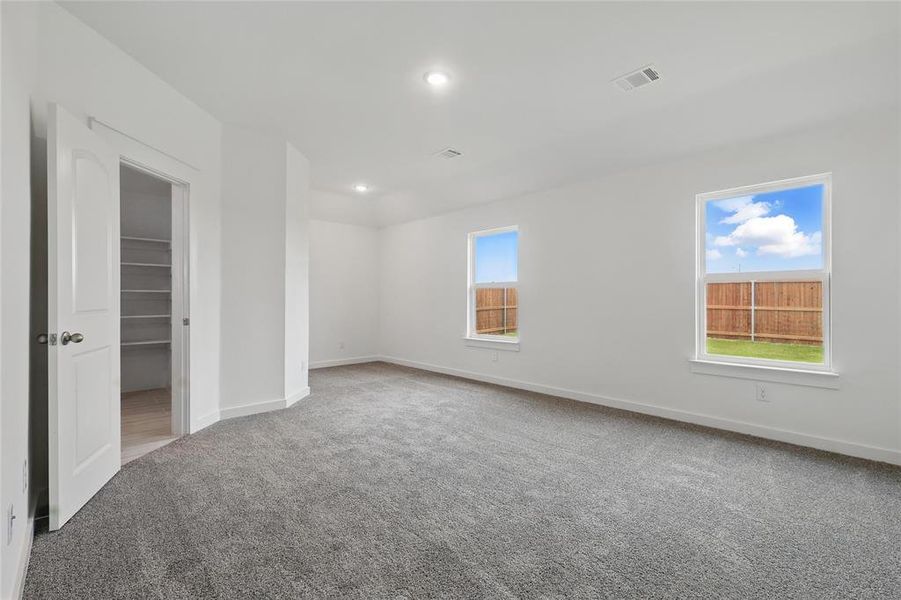 Unfurnished bedroom featuring light colored carpet, a spacious closet, multiple windows, and recessed lighting Unfurnished bedroom featuring light colored carpet, a spacious closet, multiple windows, and recessed lighting