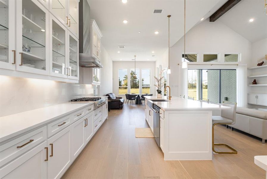 Kitchen featuring open floor plan, white cabinets, hanging light fixtures, a breakfast bar, and recessed lighting