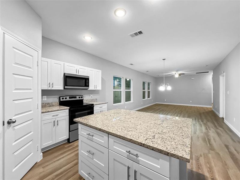 Kitchen with light wood-type flooring, white cabinetry, a kitchen island, and stainless steel appliances