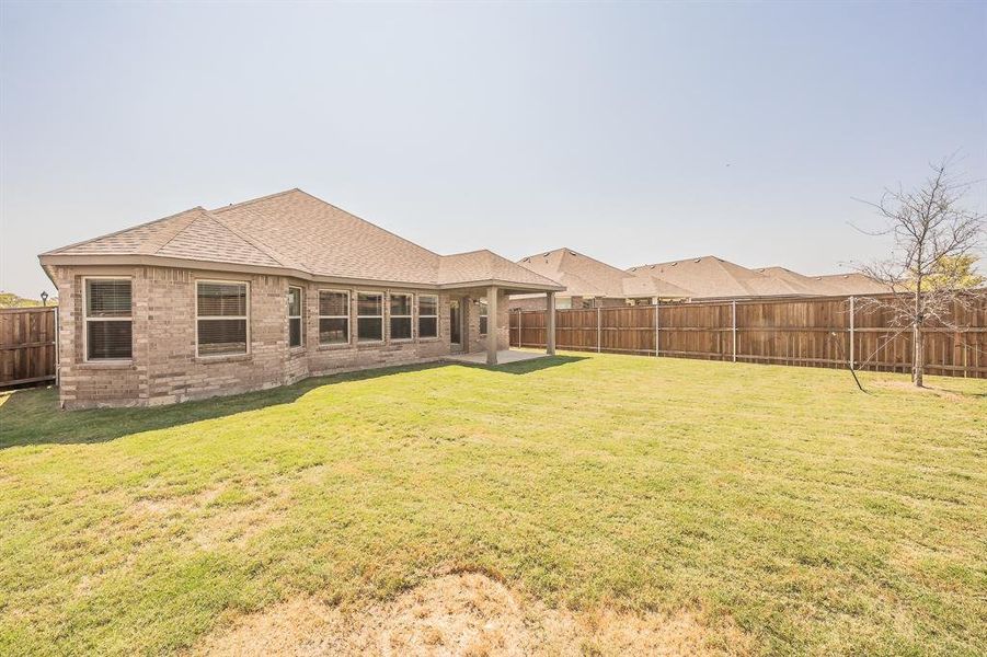 Rear view of property featuring a patio area, a fenced backyard, roof with shingles, and brick siding Rear view of property featuring a patio area, a fenced backyard, roof with shingles, and brick siding