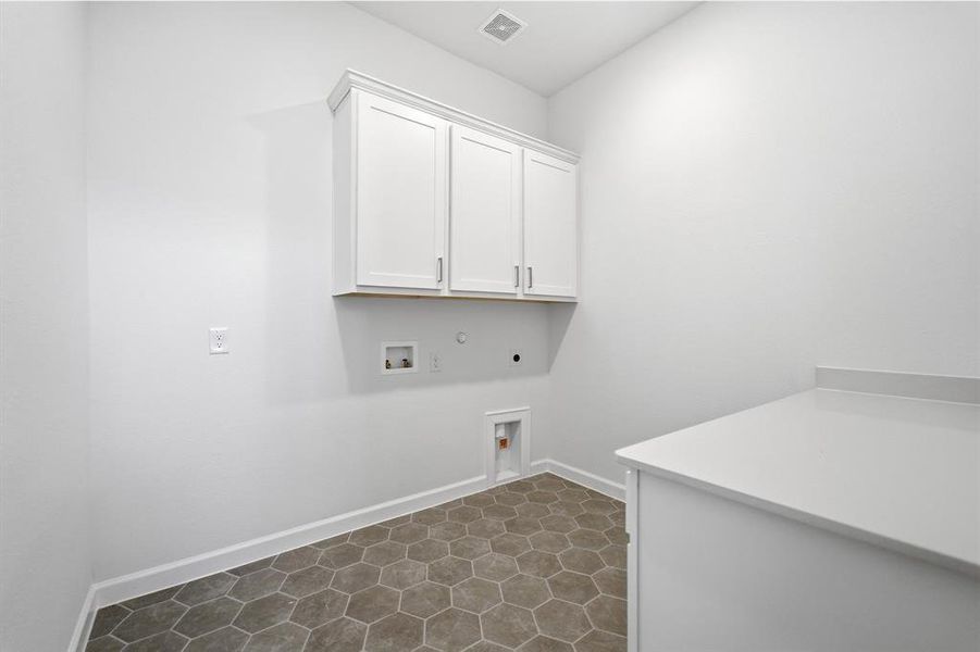 Dedicated utility space featuring white shaker-style cabinetry, a built-in counter, and hexagonal tile flooring