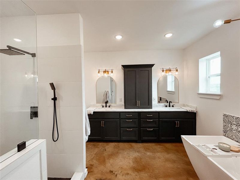 Full bathroom with walk in shower, double vanity, a soaking tub, concrete flooring, and recessed lighting Full bathroom with walk in shower, double vanity, a soaking tub, concrete flooring, and recessed lighting